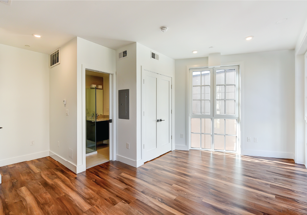an empty living room with a hard wood floor and white walls