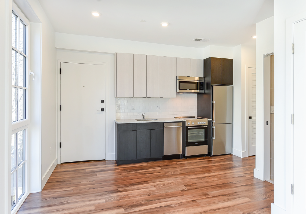 an empty kitchen with a wooden floor and white cabinets