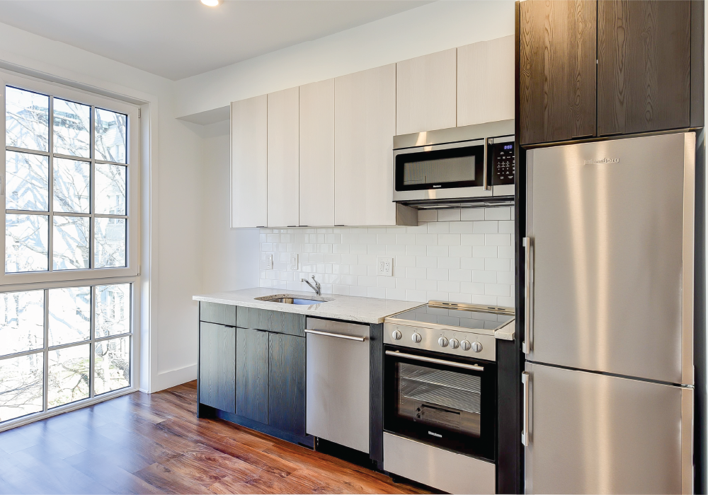 an empty kitchen with stainless steel appliances and white cabinets