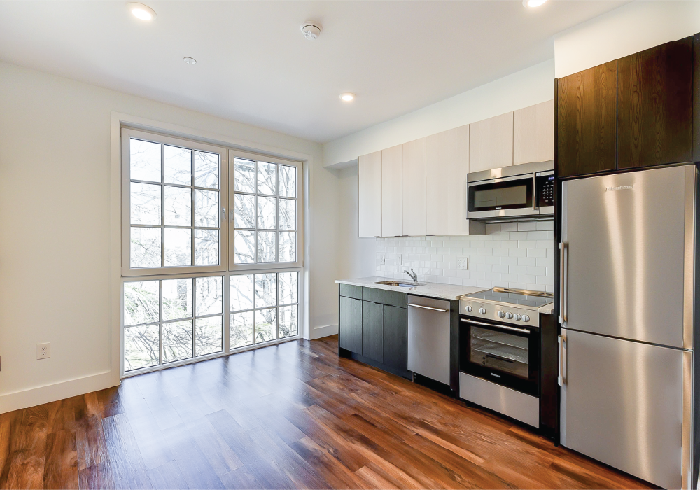 an empty kitchen with stainless steel appliances and a window