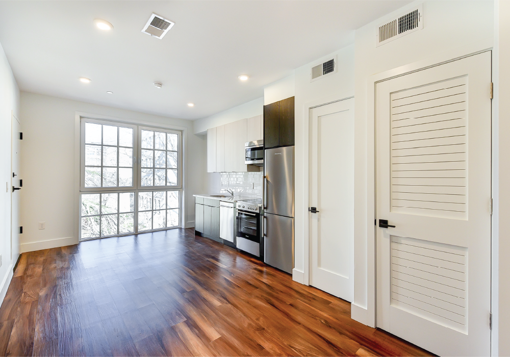 an empty living room and kitchen with wood floors and white doors