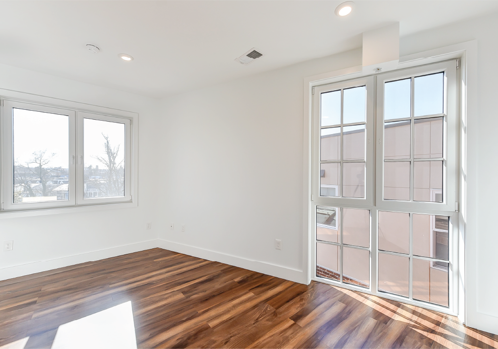a living room with wood flooring and a door to a balcony