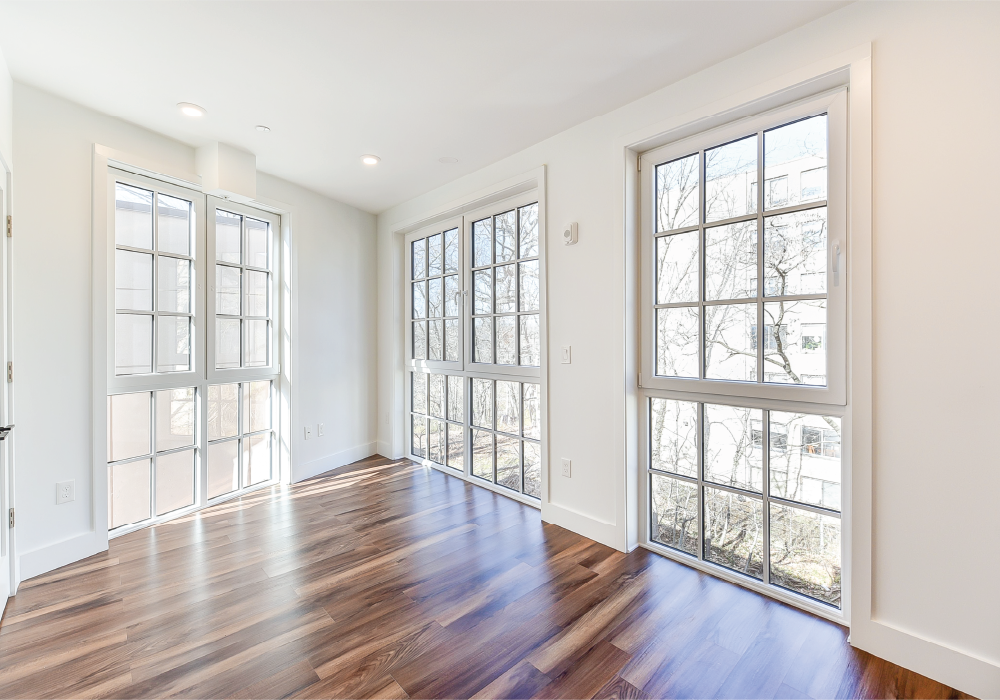 an empty living room with wood floors and large windows