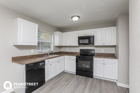 a kitchen with white cabinets and granite counter tops and black appliances