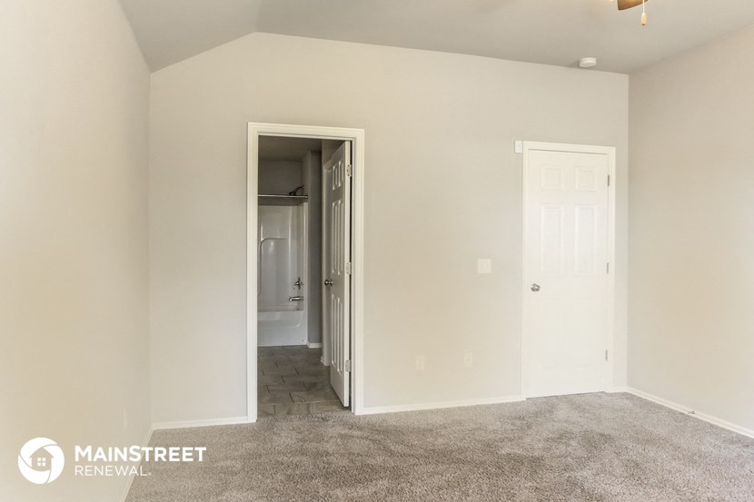 a master bedroom with a carpeted floor and a door to the bathroom