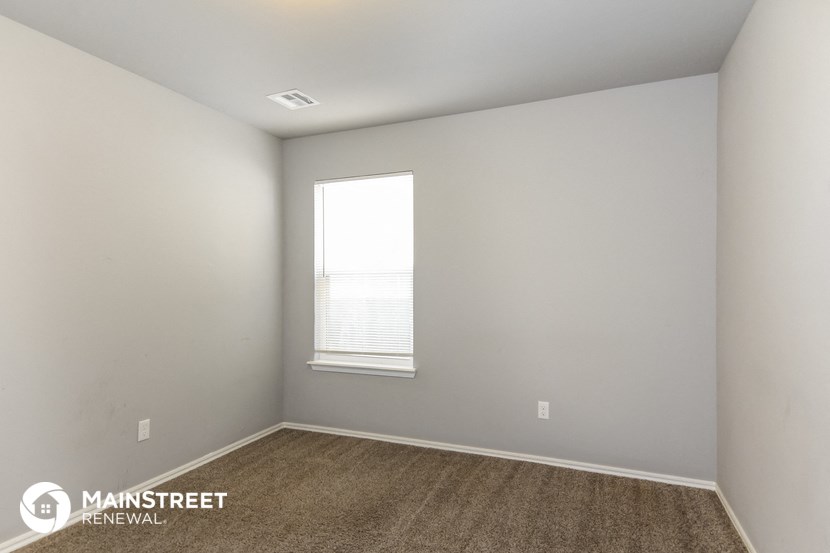 the bedroom of an apartment with white walls and a window