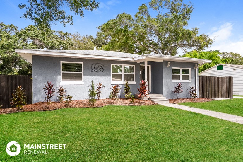 a small gray house with a lawn and a sidewalk