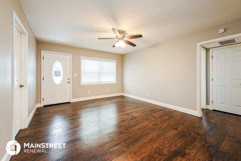 an empty living room with wood floors and a ceiling fan