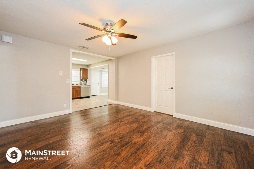an empty living room with a ceiling fan and wood floors