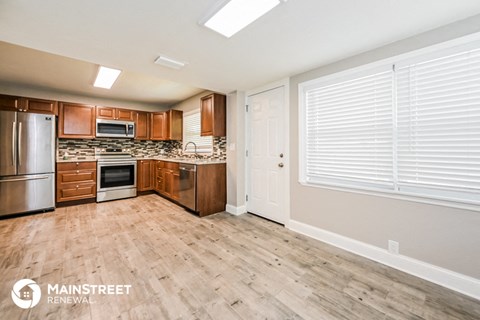 a kitchen with wood flooring and wooden cabinets and stainless steel appliances