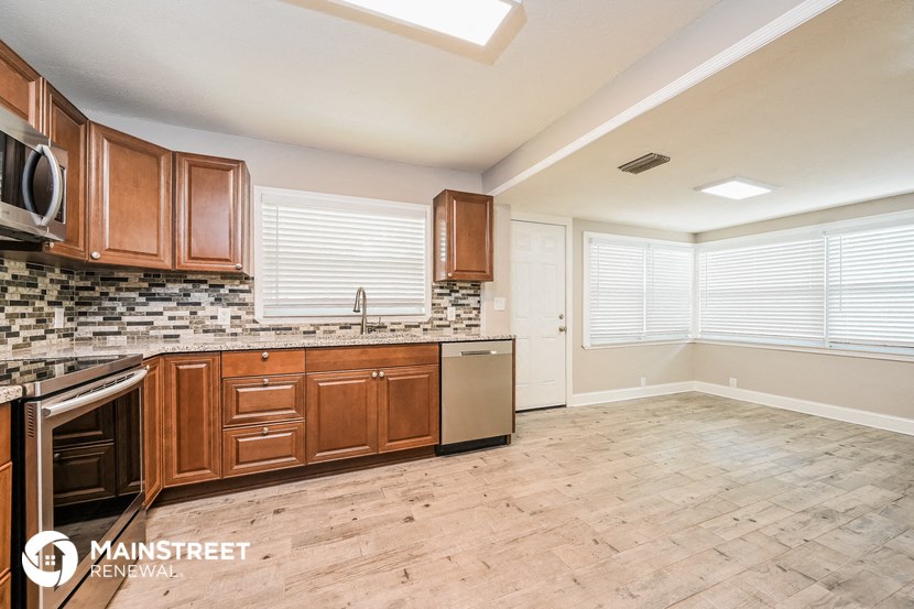 a kitchen with wooden cabinets and a stainless steel dishwasher and a window