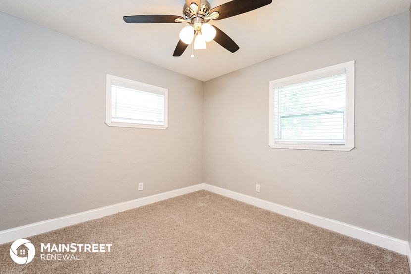 the bedroom has a ceiling fan and two windows