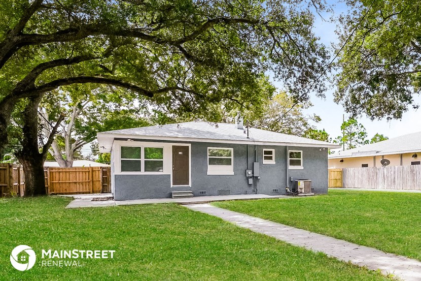 a small gray house with a yard and a tree
