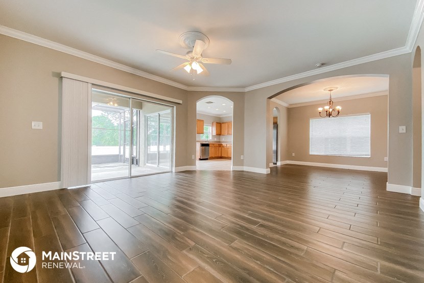 an empty living room with wood floors and a ceiling fan