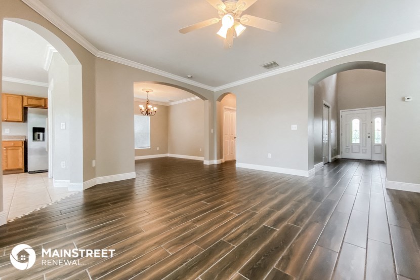 an empty living room with wood flooring and a ceiling fan