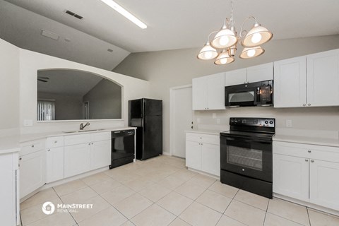 a large kitchen with white cabinets and black appliances