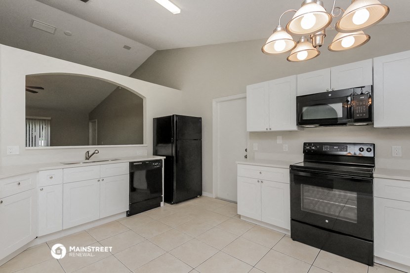 a white kitchen with black appliances and white cabinets