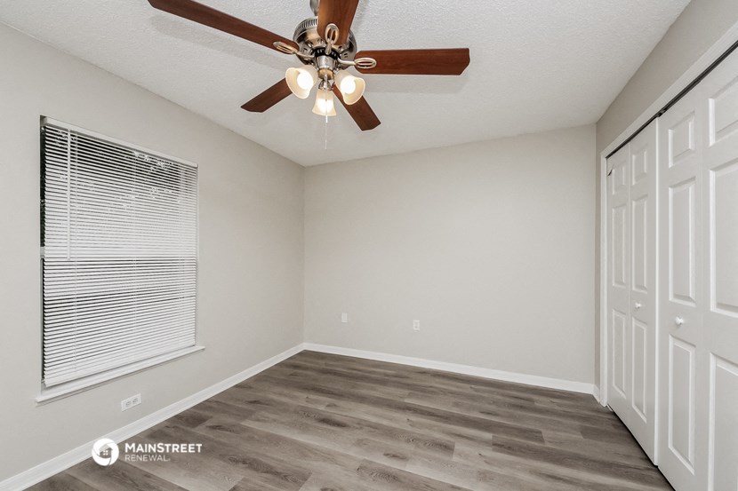 the spacious living room has a ceiling fan and a large window
