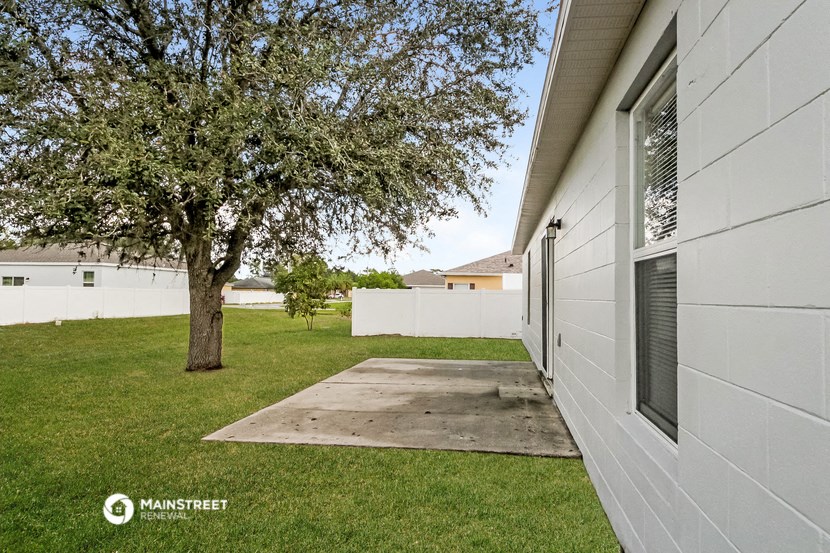 the driveway to the side of a house with a tree