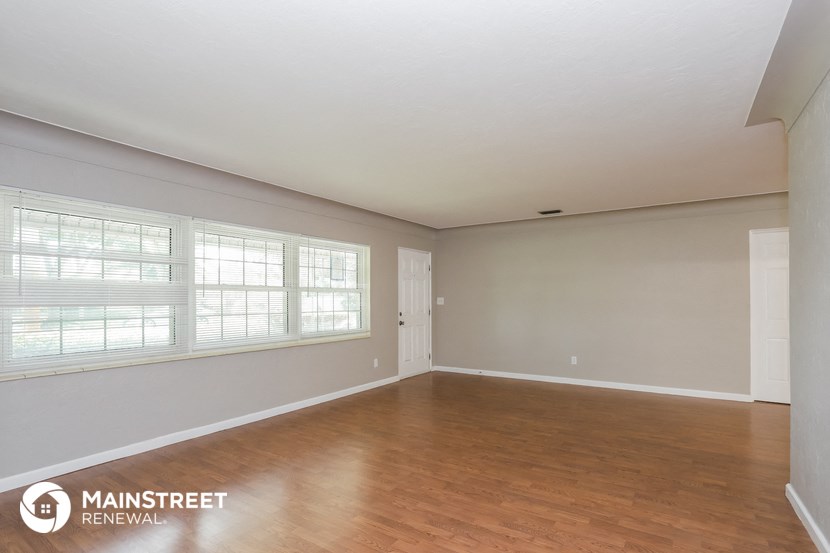 the spacious living room with wood flooring and large windows