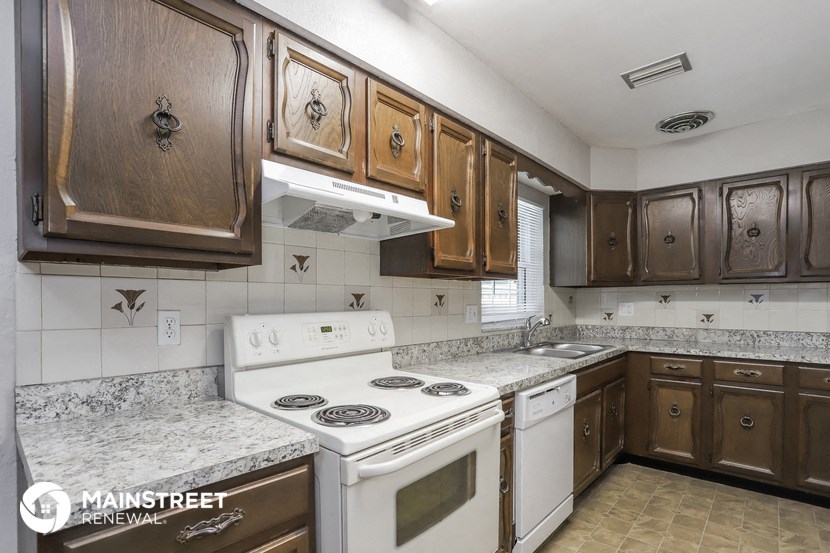 a kitchen with white appliances and wooden cabinets and marble counter tops
