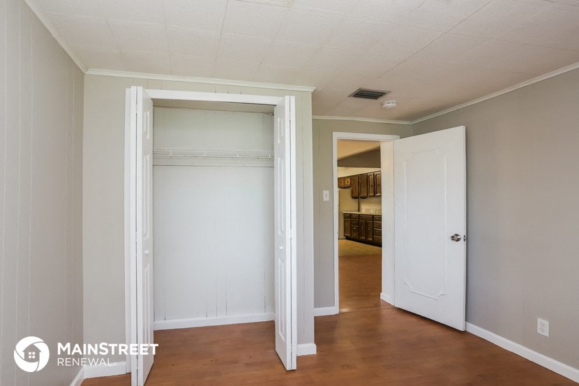 a room with two doors and a hallway with a door to a closet and a