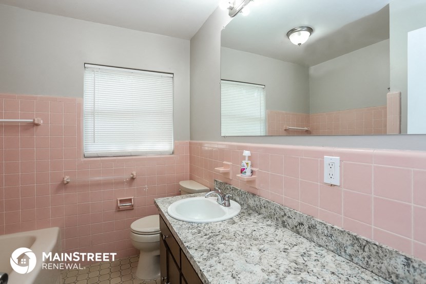 a bathroom with pink tiles and a sink and a toilet