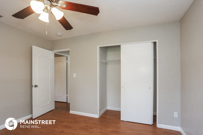 an empty room with a ceiling fan and two closets