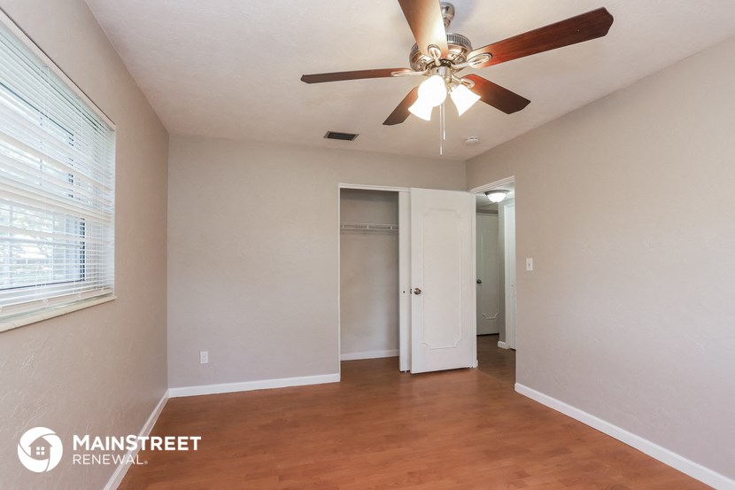 an empty living room with a ceiling fan and a closet