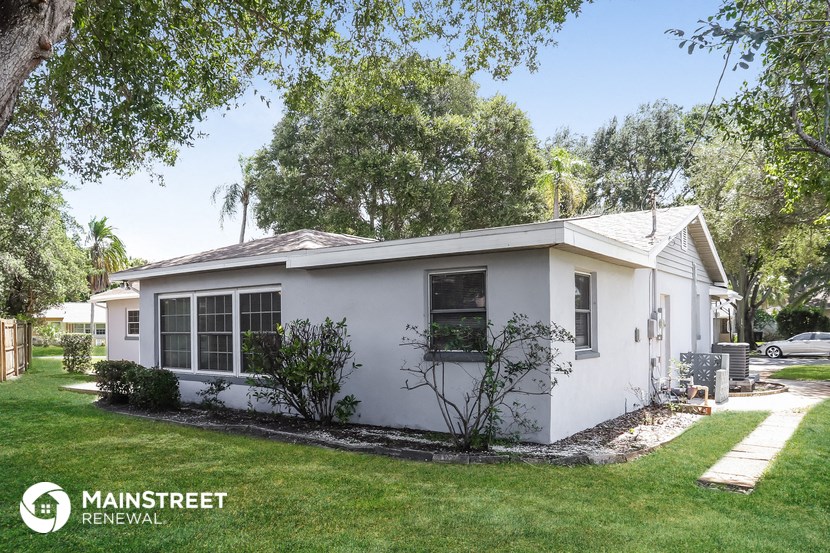 a small white house with a lawn and trees