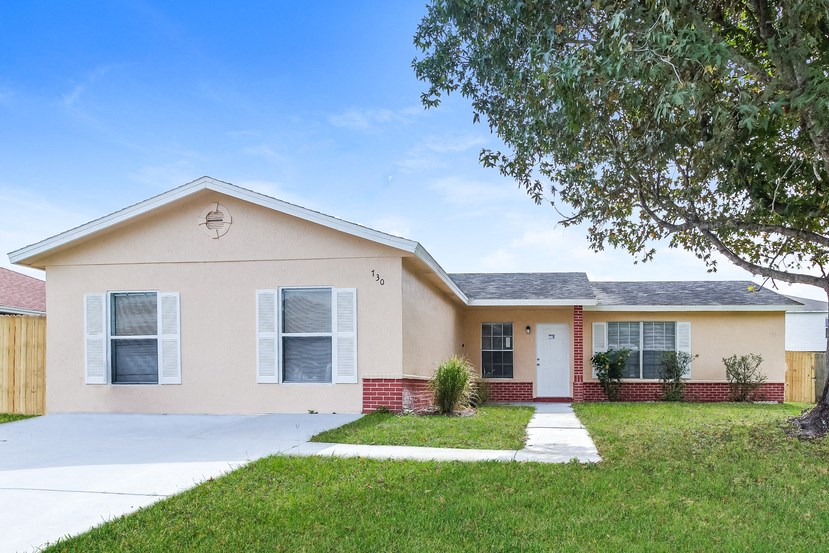a beige house with a sidewalk in front of a yard