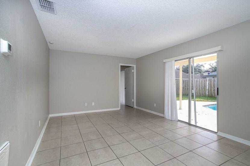 an empty living room with a sliding glass door to a pool