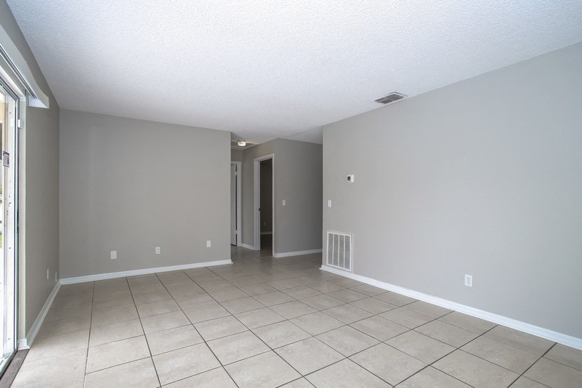 an empty living room with a tile floor and grey walls