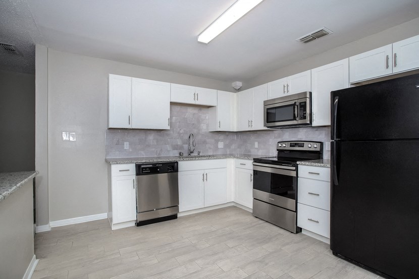 an empty kitchen with stainless steel appliances and white cabinets