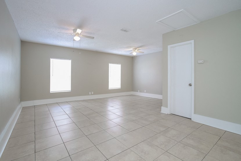 an empty living room with tile floors and a ceiling fan
