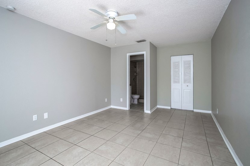 an empty living room with a ceiling fan and a tiled floor