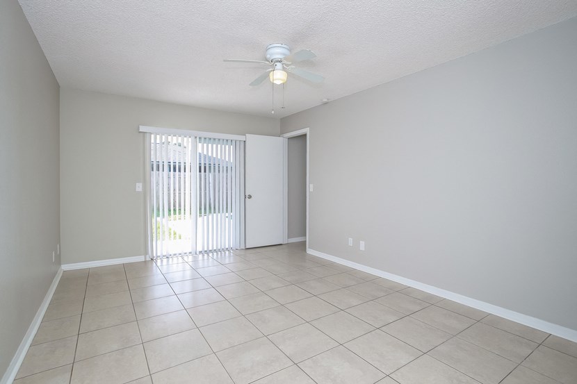 an empty living room with a ceiling fan and a sliding glass door