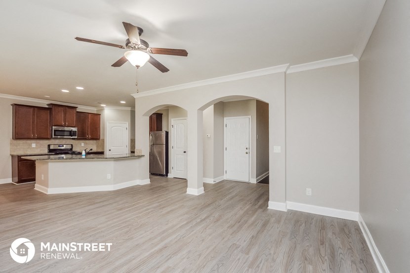 an open kitchen and living room with wood flooring and a ceiling fan
