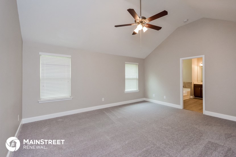 the spacious living room with ceiling fan and carpeting