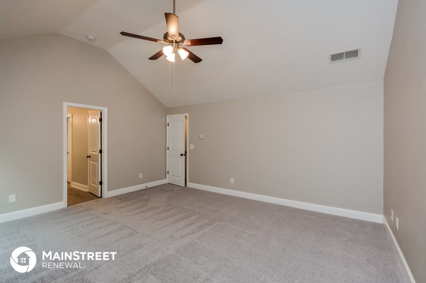 the spacious living room with ceiling fan and carpeting