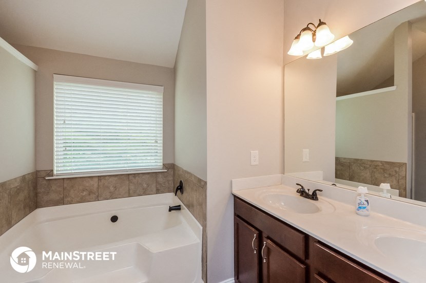 the master bathroom has a large tub and a sink and a mirror