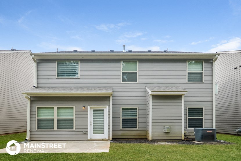 a white house with sage green shutters and a blue sky