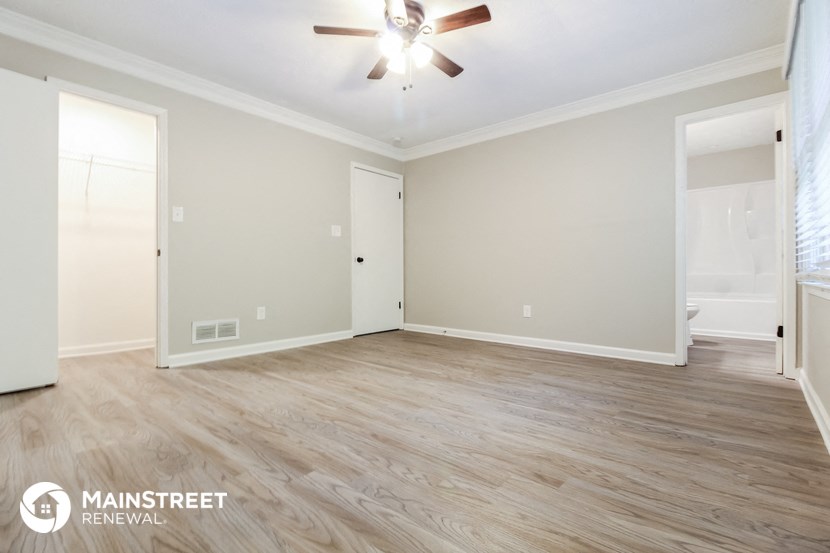 the spacious living room with wood flooring and a ceiling fan