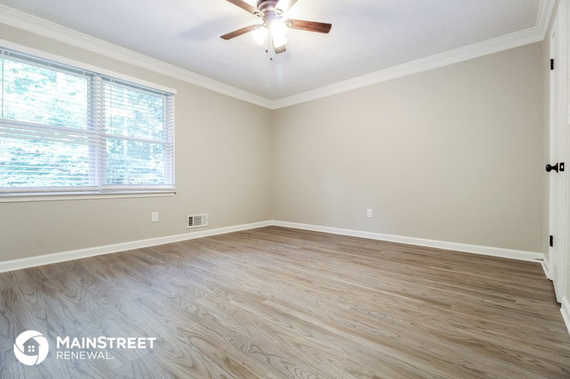 the spacious living room with hardwood flooring and a ceiling fan