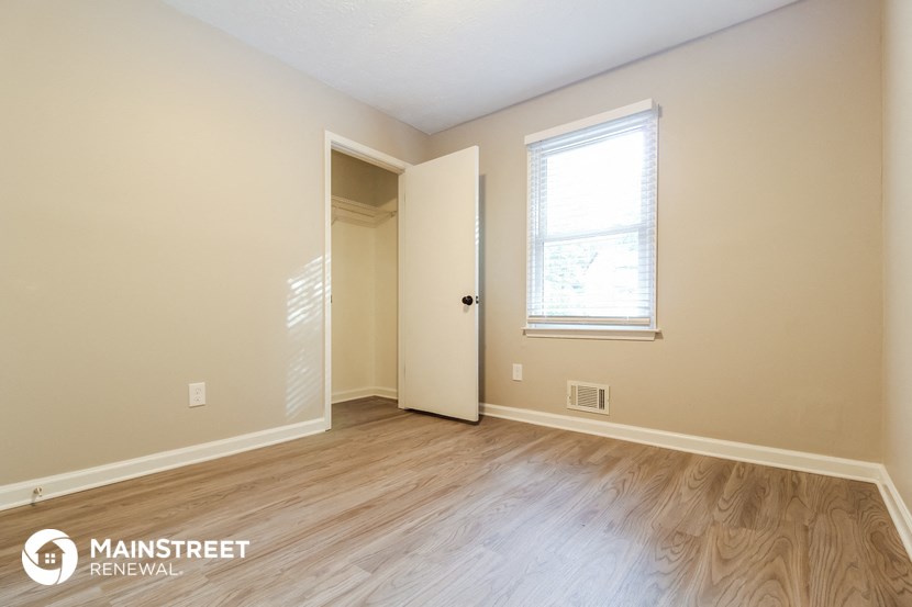 the upstairs bedroom with hardwood flooring and a door to the bathroom