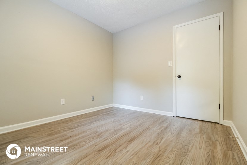 the spacious living room with wood flooring and white walls