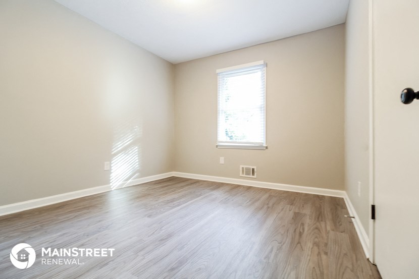 the upstairs bedroom with hardwood flooring and a window