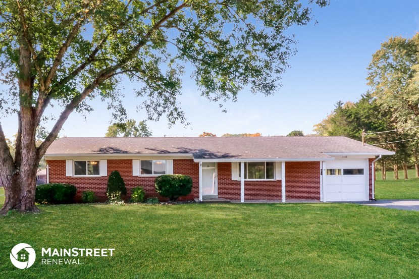 a red brick house with a lawn and a tree