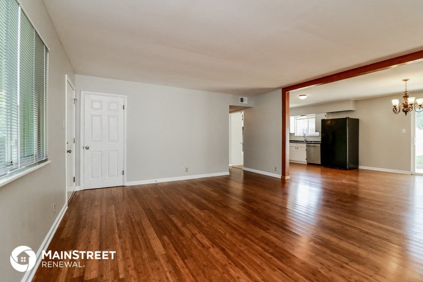 the living room and dining room of an empty house with wood flooring