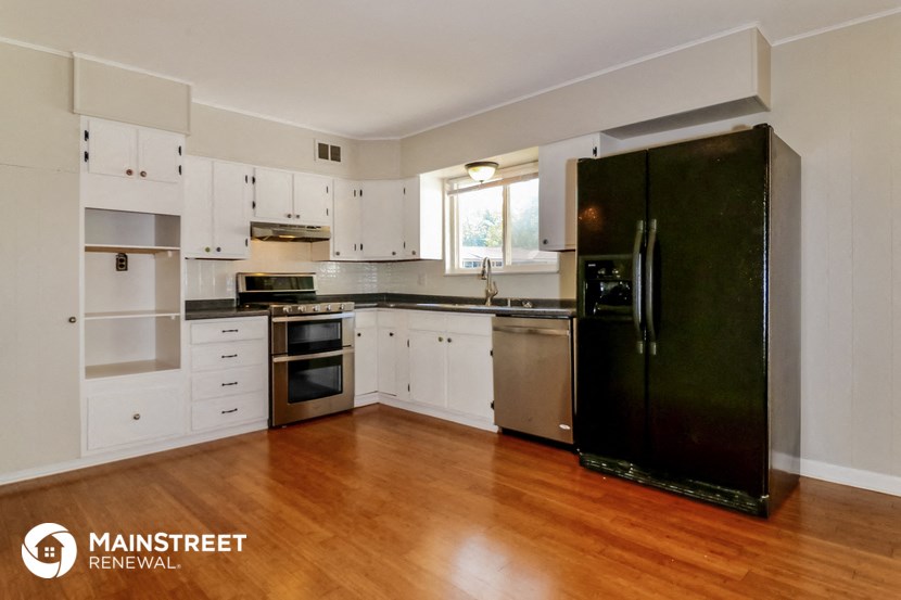 a large white kitchen with stainless steel appliances and wood floors